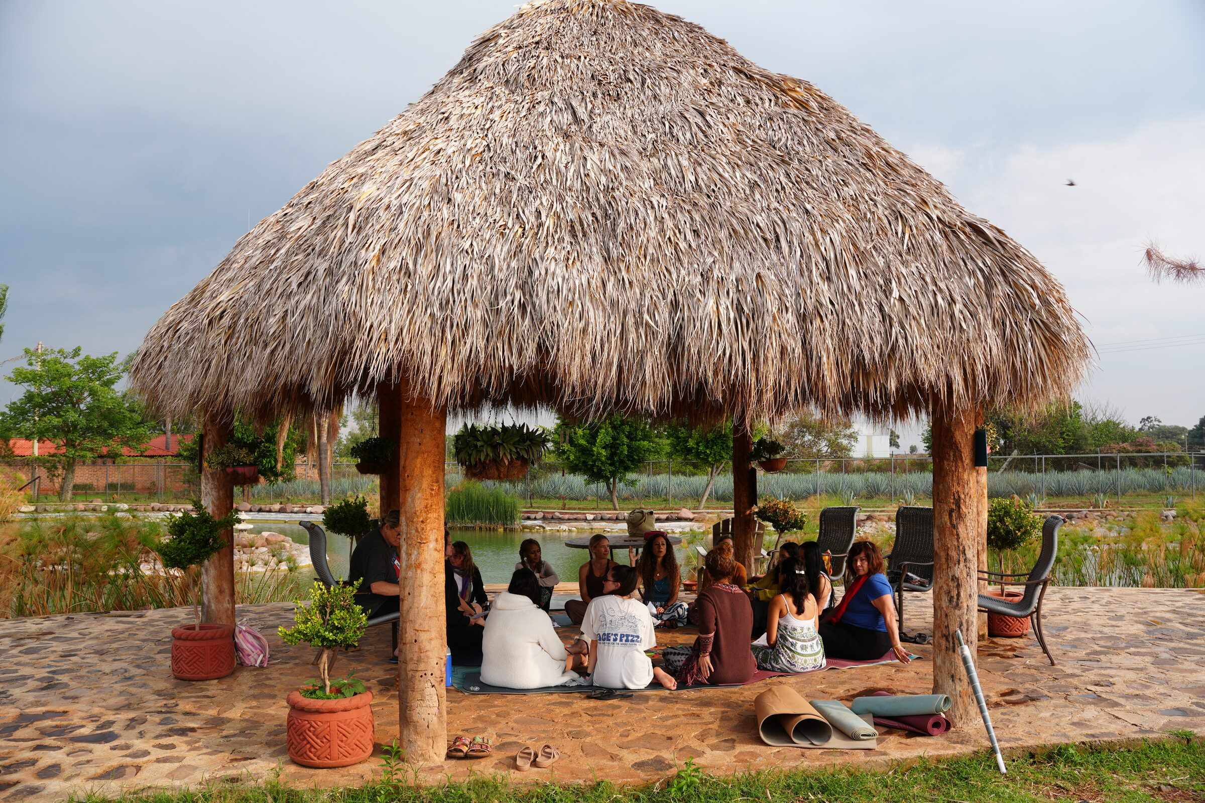 A circle gathered under the palapa by the lake