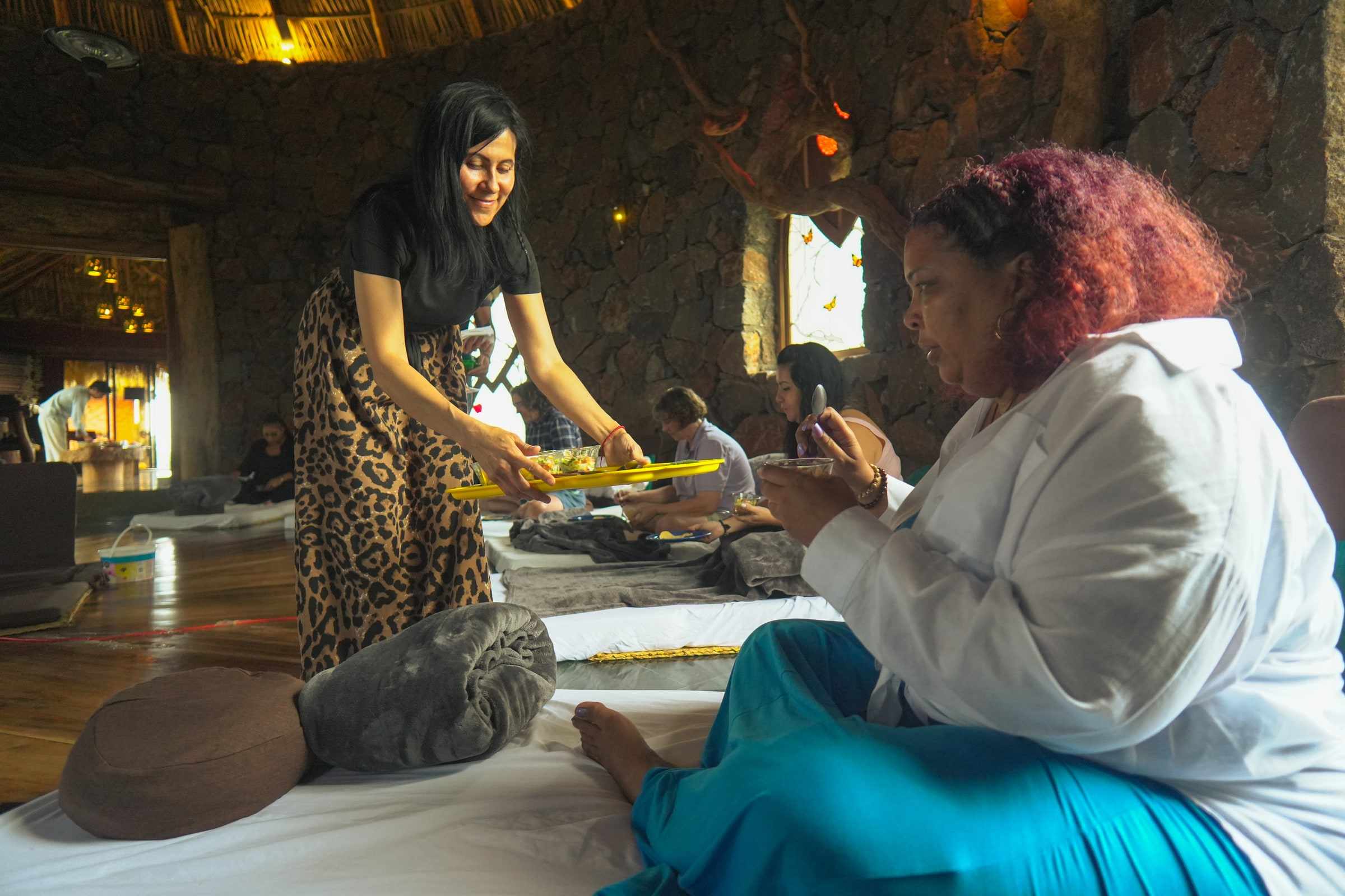 A facilitator serving guests seated inside the Osho Hut