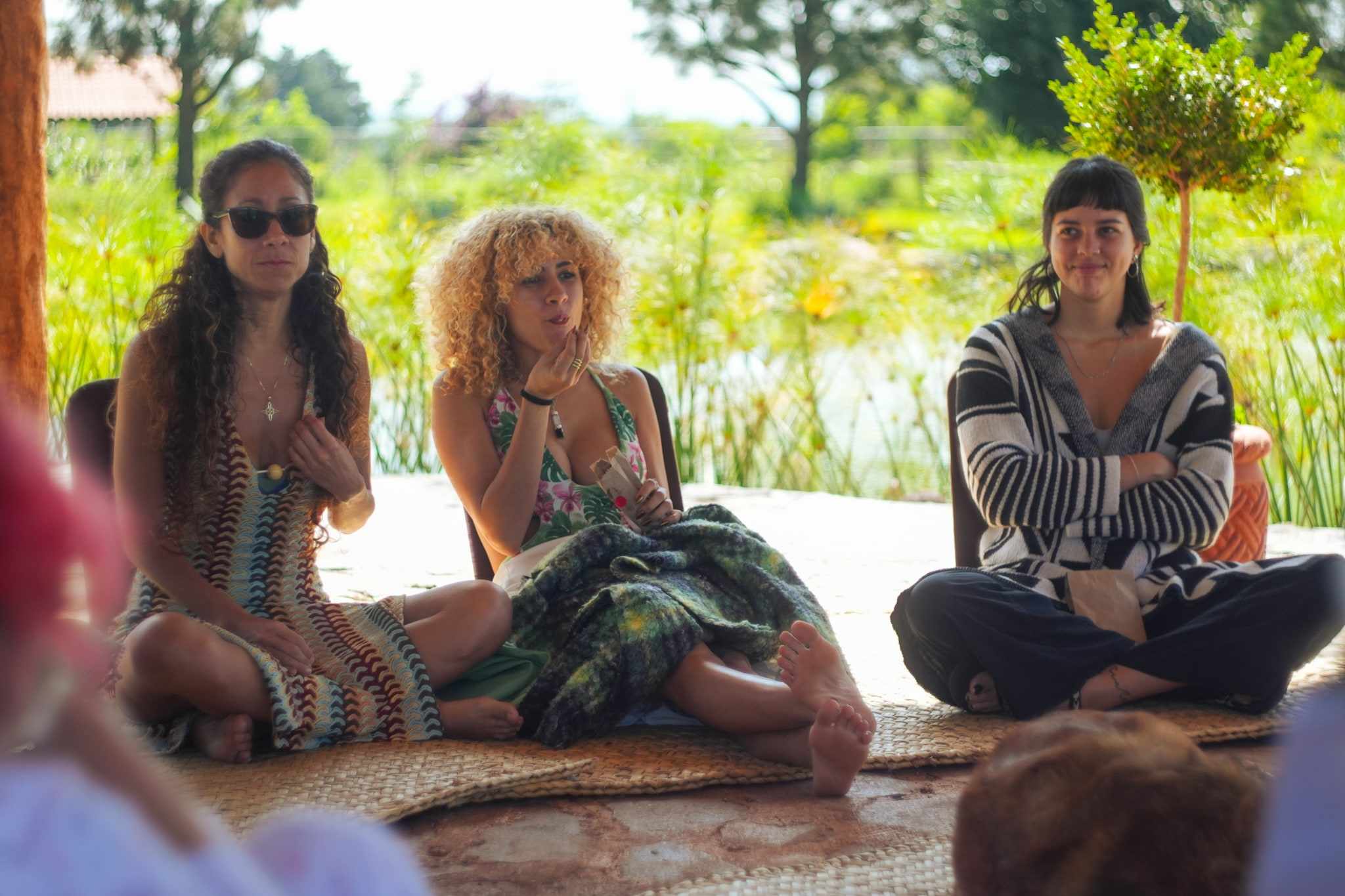 Three women sitting in a circle by the lake