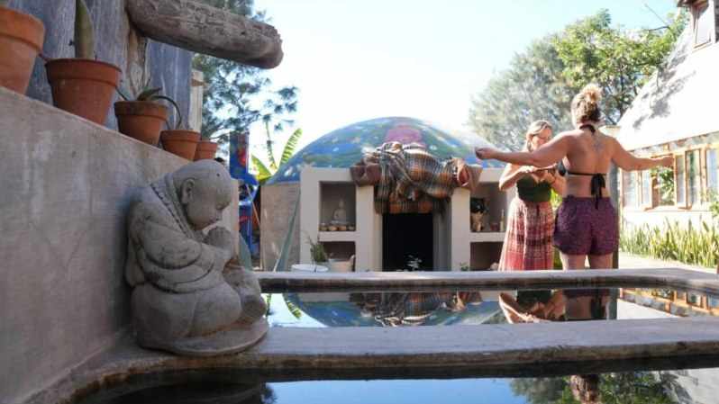 The painted temazcal dome behind the cold-water tubs