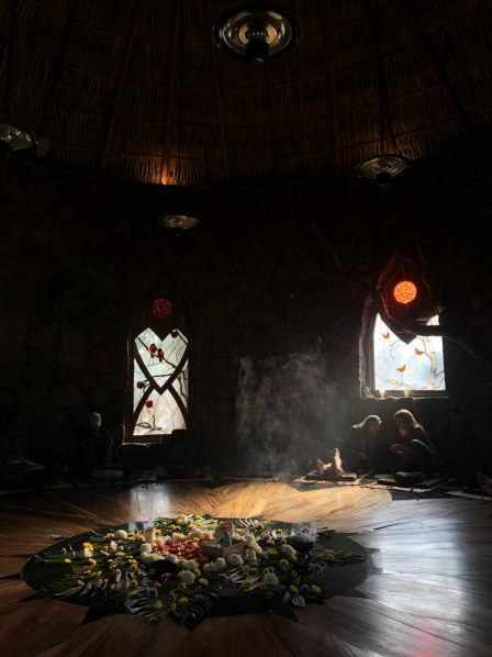 Smoke and light over a flower altar inside the Osho Hut
